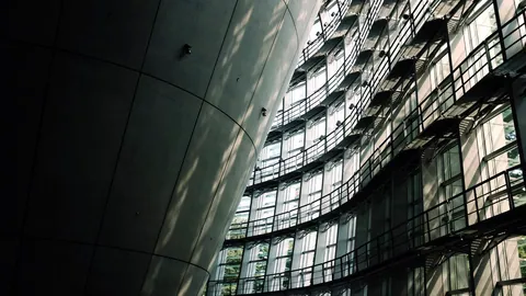 A sweeping curved concrete wall of a museum catching the morning light.