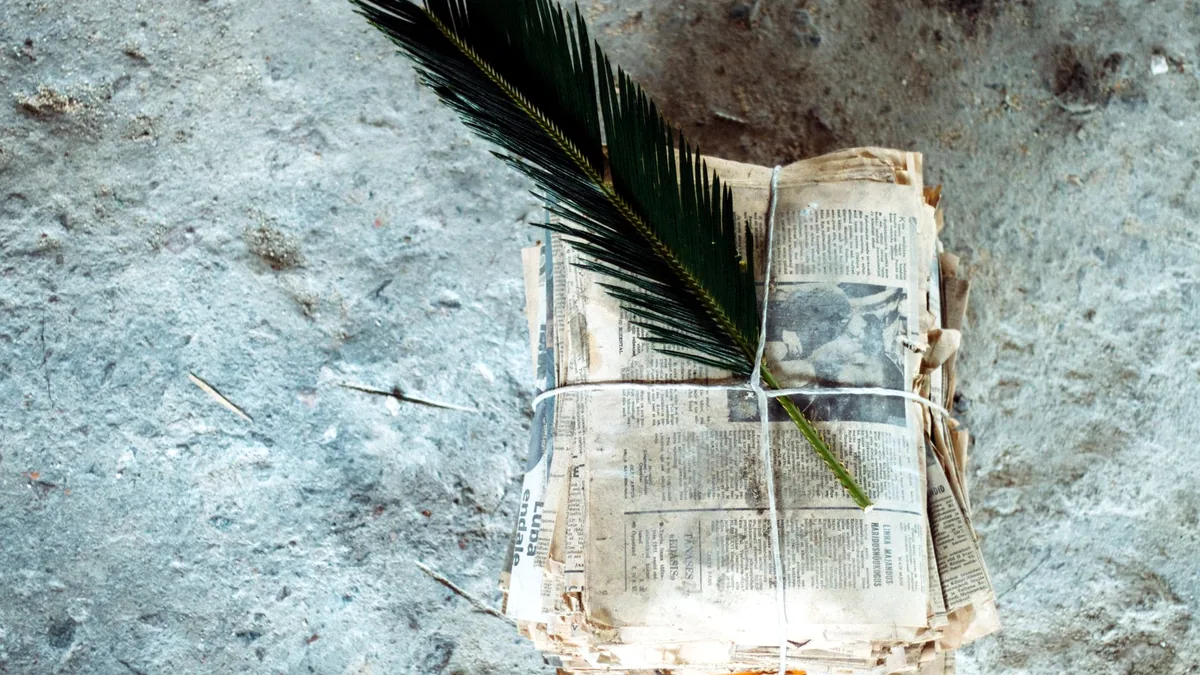 A stack of old newspaper clippings tied with a thin string.