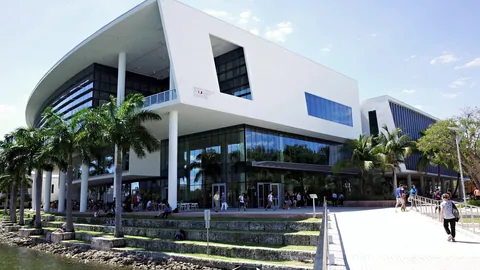 Students walking past a modern campus building on a sunny day.