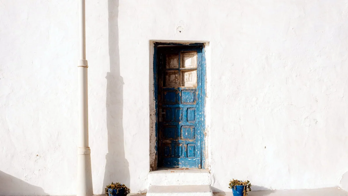 White plastered walls with bright blue doors in the sun.