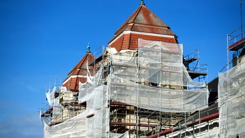 Scaffolding wrapped around the side of a building under construction.