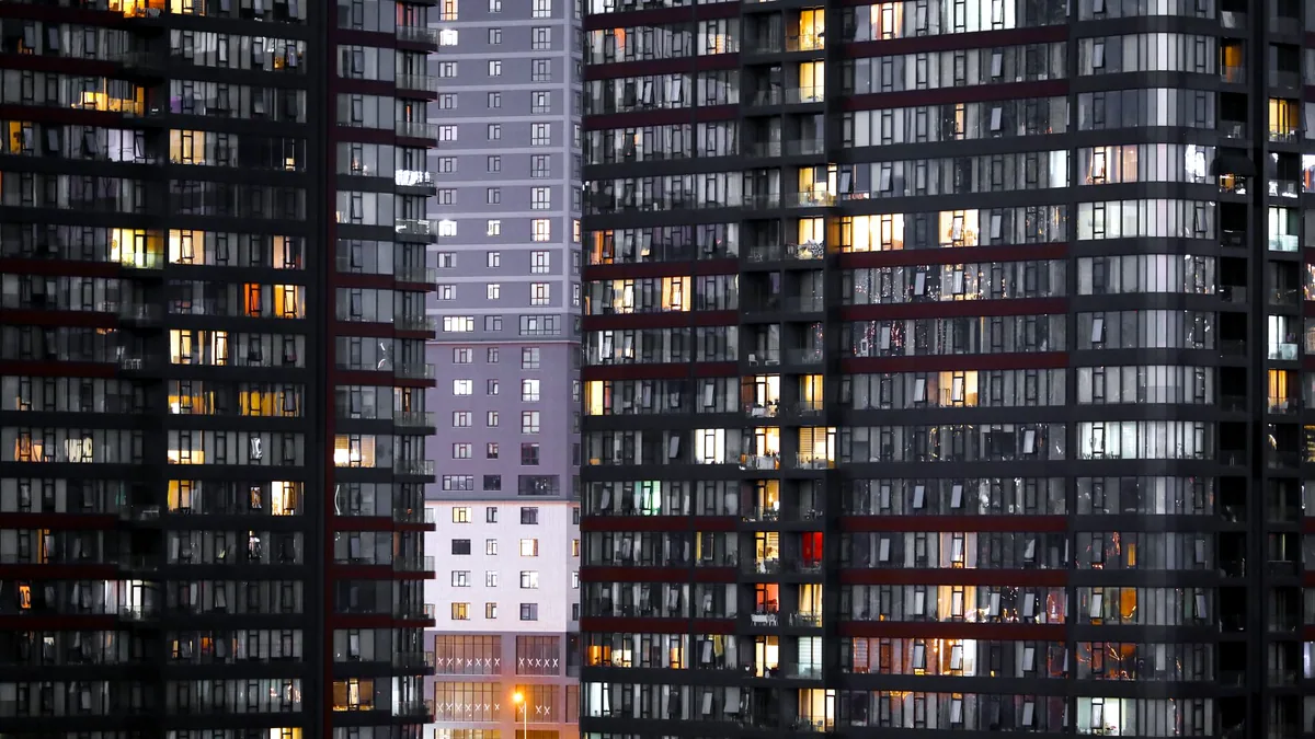 The glass and steel facade of a modern building glowing at dusk.