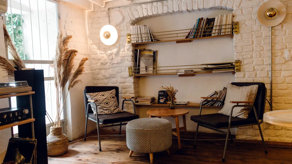 A calm living room with a tall bookshelf and soft daylight.