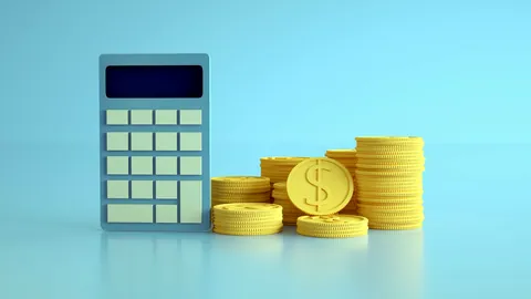 A small pile of coins sitting beside a desktop calculator.