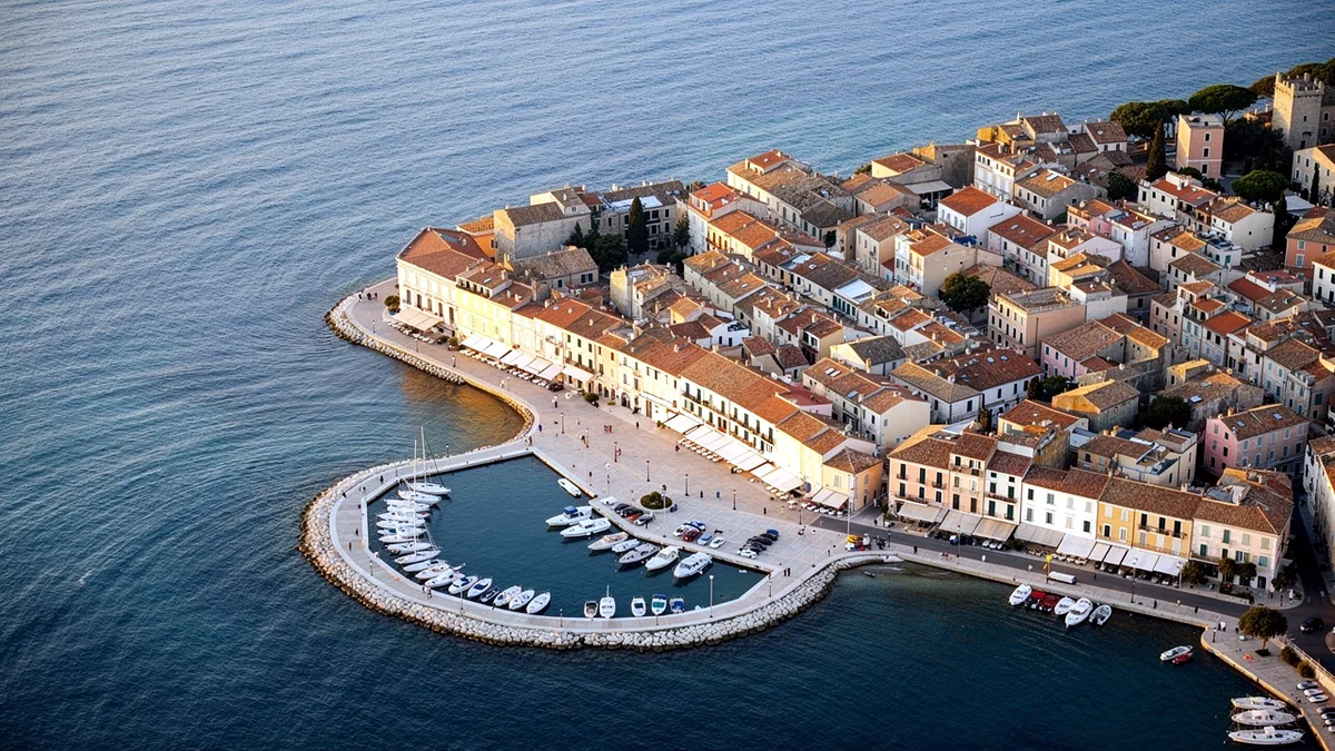 Illustration: An aerial view of a coastal town laid out in a pale street grid at golden hour.