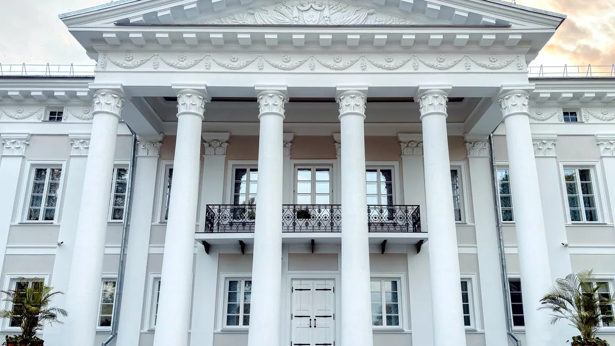 A white neoclassical building with tall columns under a clear sky.