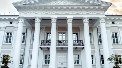 A white neoclassical building with tall columns under a clear sky.